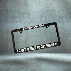 May include: Black metal license plate frame with the text "Forgive Me I Can't Afford To Get Rid Of It" in white lettering.