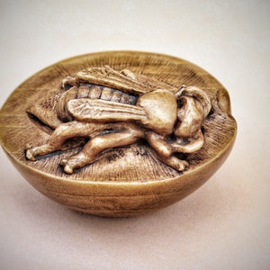 May include: A small, round, gold-colored box with a detailed carving of a fly on the lid.