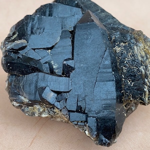 May include: A large, black, crystal cluster with a rough, natural texture. The crystal points are sharp and well-defined, and the overall shape is irregular. The crystal is a dark, opaque black color.