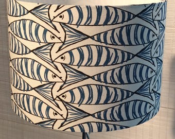 May include: A white lampshade with a blue and white fish pattern. The fish are arranged in a repeating pattern, with their tails pointing towards the bottom of the lampshade.