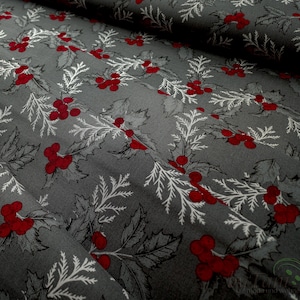 Op de afbeelding: Grijze stof met een herhalend patroon van rode bessen, witte takken en grijze bladeren. De stof is gevouwen, wat de textuur en het ontwerp laat zien. Ideaal voor knutsel- en naaiprojecten met een feestthema.