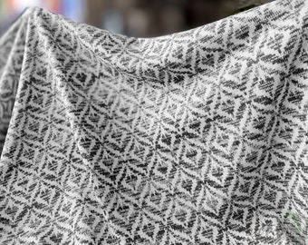 May include: White fabric with a black geometric pattern. The fabric is folded and draped.