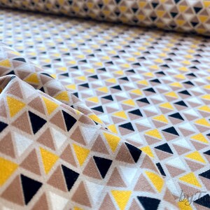 May include: Fabric with a geometric pattern of yellow, brown, black and white triangles.