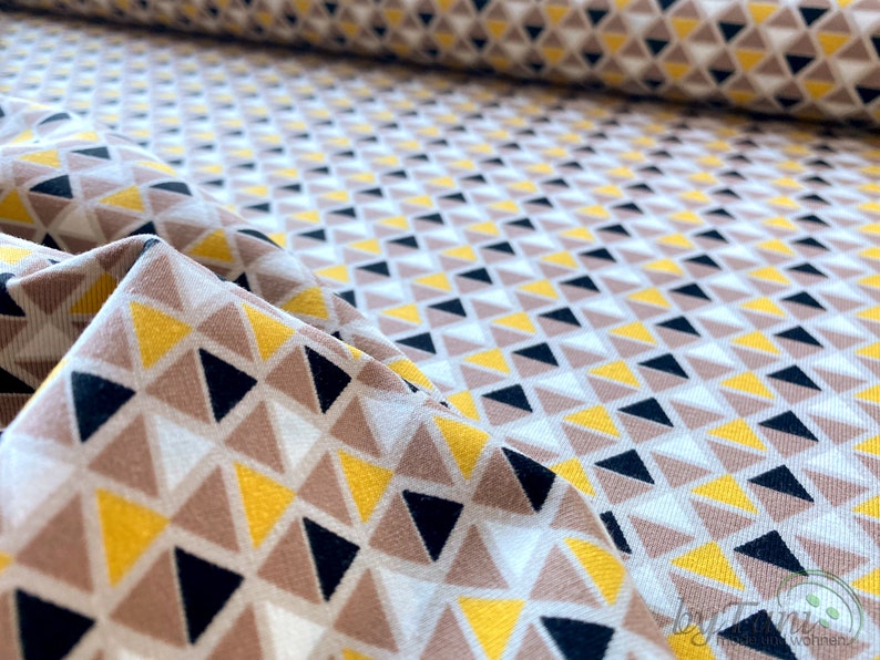 May include: Fabric with a geometric pattern of yellow, brown, black and white triangles.