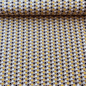 May include: A fabric with a repeating pattern of small triangles in brown, yellow, white and black.