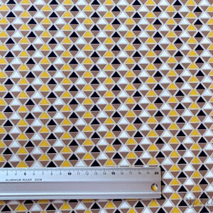 May include: A white fabric with a repeating pattern of small yellow, brown, and black triangles.