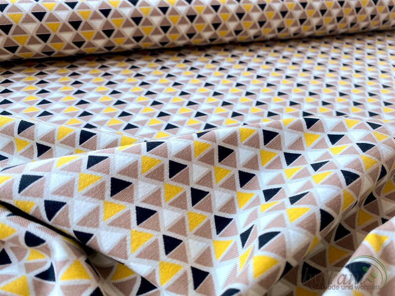 May include: White fabric with a geometric pattern of yellow, brown, and black triangles.