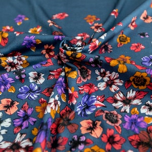 May include: A teal blue fabric with a floral print. The flowers are in shades of red, orange, purple, and white.