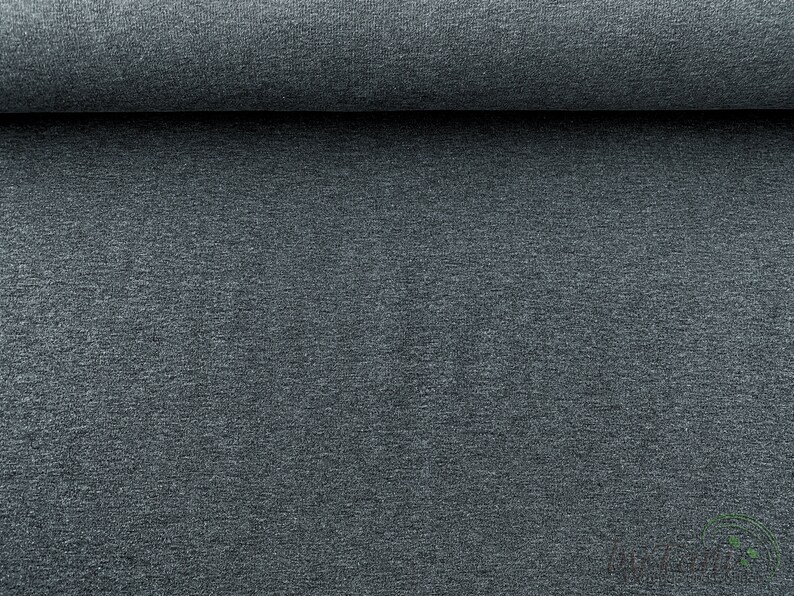 May include: Close-up of a dark gray fabric with a textured surface. The fabric is rolled up and the texture is visible.