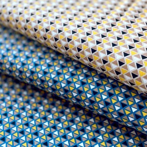 May include: Two fabric swatches with a geometric pattern of small triangles in shades of brown, yellow, white, and blue.