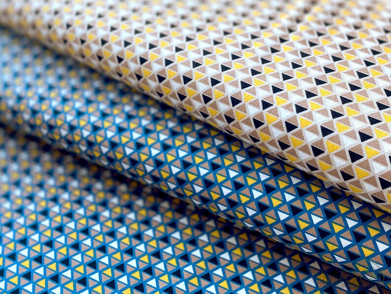 May include: Two fabric swatches with a geometric pattern of small triangles in shades of brown, yellow, white, and blue.
