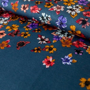 May include: A teal blue fabric with a floral print. The flowers are in shades of orange, red, purple, and white.