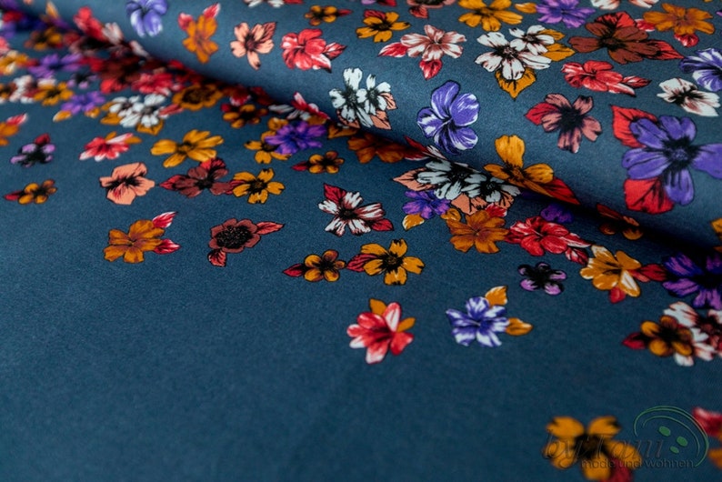 May include: A teal blue fabric with a floral print. The flowers are in shades of orange, red, purple, and white.