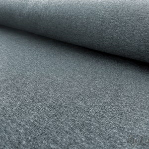 May include: Close-up of a gray, textured fabric. The fabric has a soft, slightly fuzzy appearance.