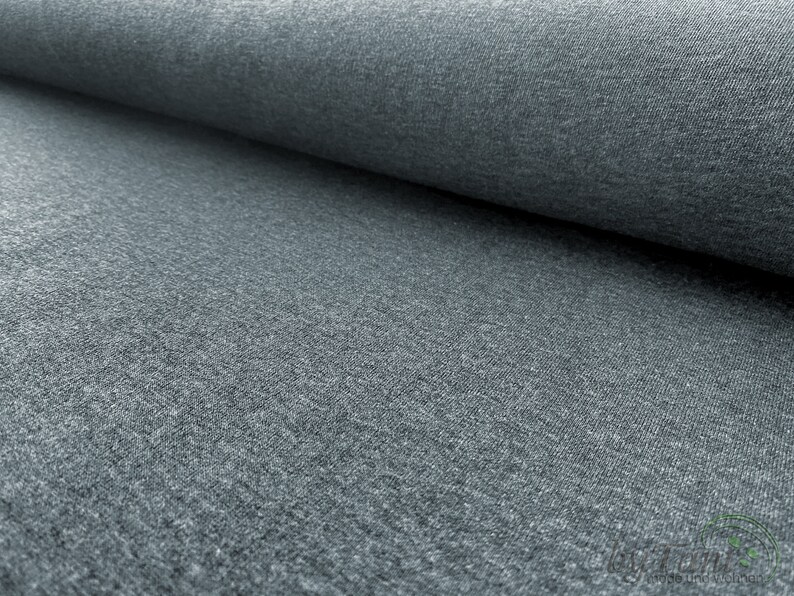 May include: Close-up of a gray, textured fabric. The fabric has a soft, slightly fuzzy appearance.
