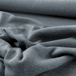 May include: A close-up of a soft, gray fabric with a textured surface. The fabric is folded and draped, showing its texture and drape.