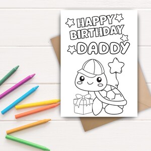 May include: A black and white coloring card with the text "HAPPY BIRTHDAY DADDY" and a cartoon turtle holding a gift and a star balloon. Colored pencils in green, purple, blue, yellow, and orange are scattered around the card.
