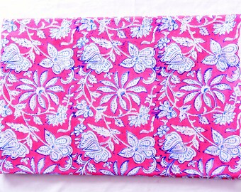 Op de afbeelding: Roze stof met een wit en blauw bloemenpatroon. De stof is dubbelgevouwen en de randen zijn zichtbaar.