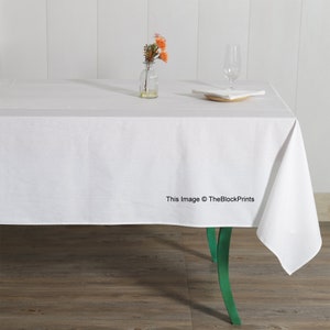 Peut inclure: Nappe rectangulaire blanche sur une table en bois avec une chaise verte. Un petit vase avec des fleurs orange et un verre sont sur la table.