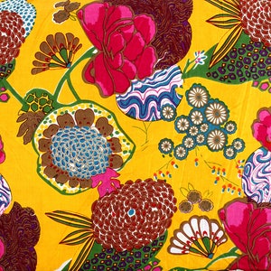 May include: A yellow fabric with a colorful floral pattern. The flowers are pink, red, blue, green, and brown. The fabric has a retro, vintage style.