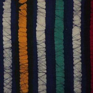 May include: A close-up of a fabric with vertical stripes in various colors, including green, orange, white, teal, and red. The stripes are on a dark blue background.