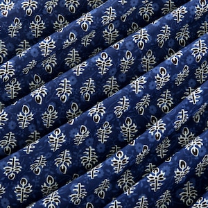 May include: Blue fabric with a white and black floral pattern. The fabric is folded in a diagonal pattern.
