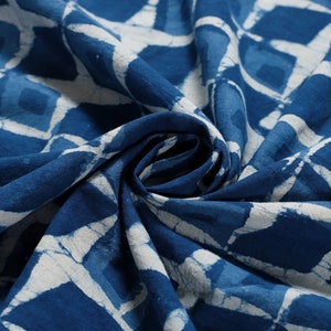 K&ouml;nnte beinhalten: Nahaufnahme eines blauen und wei&szlig;en Stoffes mit geometrischem Muster. Der Stoff ist gefaltet und zerknittert, wodurch die Textur des Materials sichtbar wird.