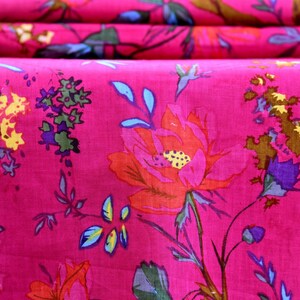 May include: Pink fabric with a floral pattern featuring large red flowers, small blue flowers, and brown leaves. The fabric also has a bird design.