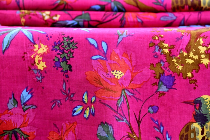 May include: Pink fabric with a floral pattern featuring large red flowers, small blue flowers, and brown leaves. The fabric also has a bird design.
