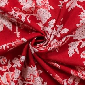 May include: Red fabric with a white floral pattern. The fabric is folded and the pattern is visible on both sides.