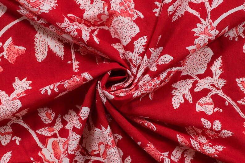 May include: Red fabric with a white floral pattern. The fabric is folded and the pattern is visible on both sides.