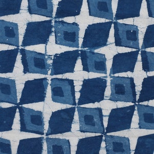 K&ouml;nnte beinhalten: Indigo blauer Stoff mit einem sich wiederholenden geometrischen Muster aus Quadraten und Rauten. Das Muster wird mit einer Resist-F&auml;rbetechnik erzeugt, die zu einer subtilen Variation des Blautons f&uuml;hrt.