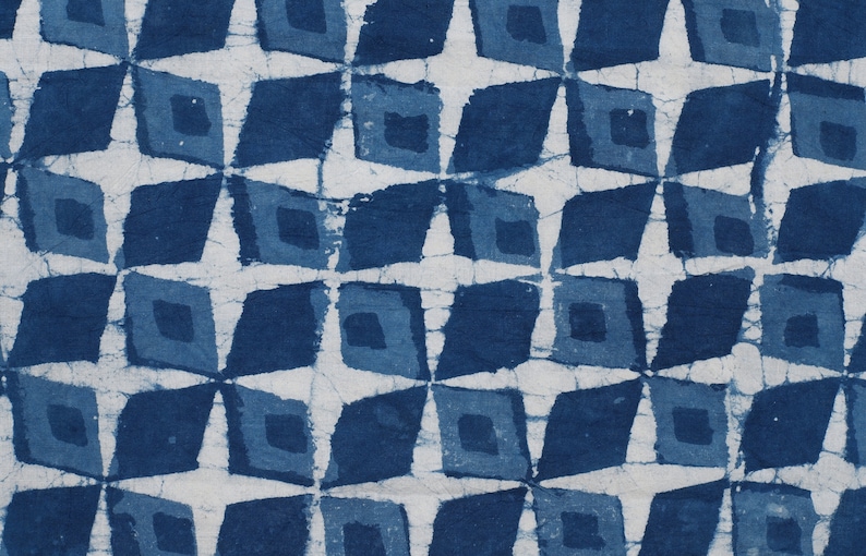 K&ouml;nnte beinhalten: Indigo blauer Stoff mit einem sich wiederholenden geometrischen Muster aus Quadraten und Rauten. Das Muster wird mit einer Resist-F&auml;rbetechnik erzeugt, die zu einer subtilen Variation des Blautons f&uuml;hrt.
