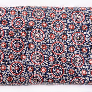 Op de afbeelding: Blauwe stof met een herhalend patroon van rode en witte cirkels met ingewikkelde ontwerpen erin. De stof heeft een traditionele Indiase stijl.