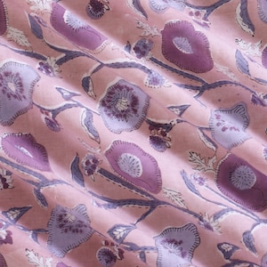 May include: Pink fabric with a floral pattern in shades of purple and white. The fabric has a subtle sheen and a soft texture.