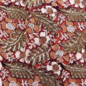 May include: A red fabric with a white and brown floral pattern. The pattern features stylized flowers, leaves, and swirls.