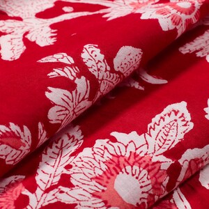 May include: Red fabric with a white floral pattern. The fabric is folded in half, showing the pattern on both sides.