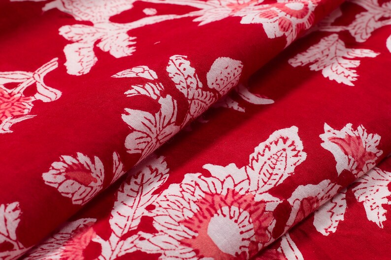 May include: Red fabric with a white floral pattern. The fabric is folded in half, showing the pattern on both sides.