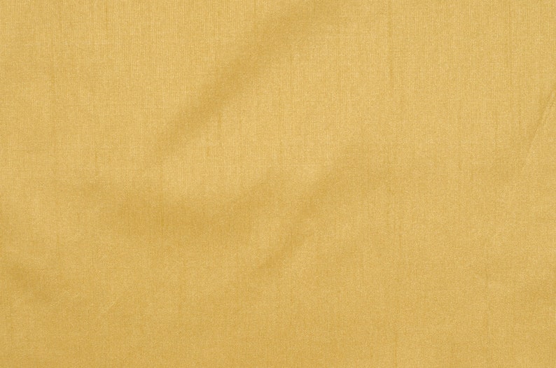 Puede incluir: Primer plano de una tela lisa de color amarillo dorado con una textura sutil. La tela tiene un ligero brillo y parece estar hecha de un material ligero.