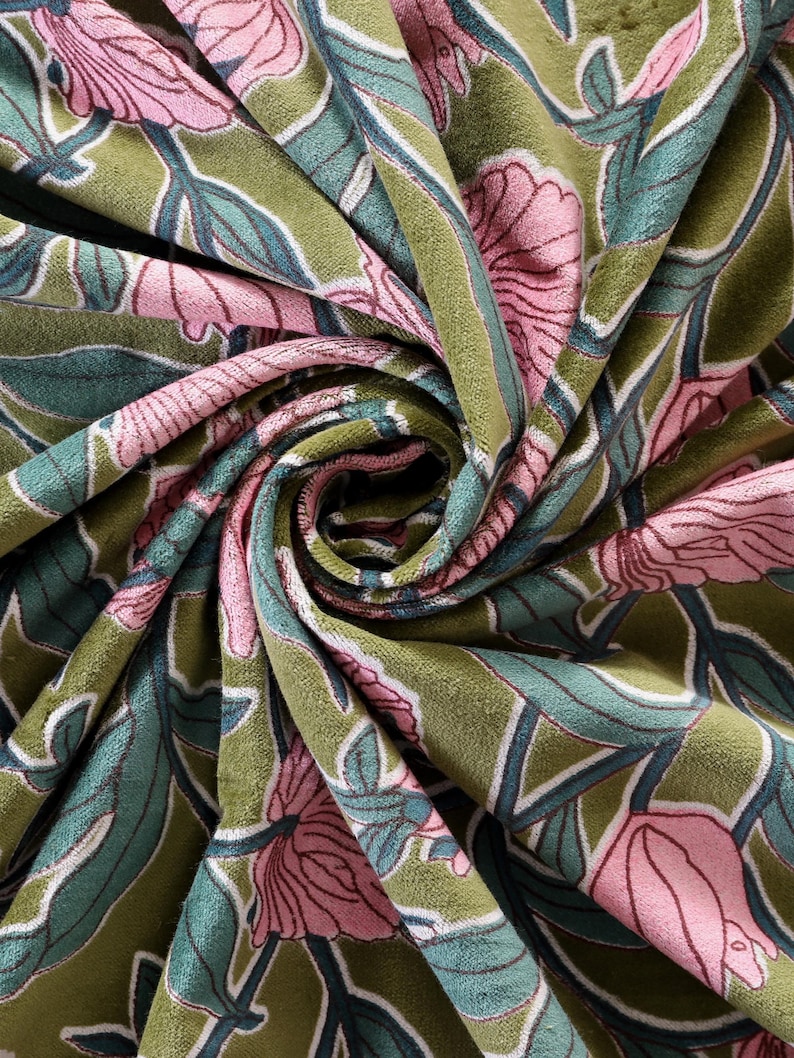 Pode incluir: Um tecido de veludo macio com um padr&atilde;o floral repetitivo de grandes flores cor-de-rosa, folhas verde-azulado e caules verde-escuros sobre um fundo verde-azeitona. O tecido est&aacute; reunido numa espiral central, real&ccedil;ando a sua textura.