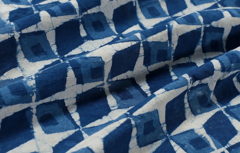 K&ouml;nnte beinhalten: Blauer und wei&szlig;er Stoff mit einem geometrischen Muster aus Quadraten. Der Stoff ist gefaltet und hat eine weiche, strukturierte Haptik.