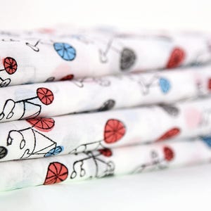May include: A stack of white fabric with a repeating pattern of black bicycles with red and blue wheels.