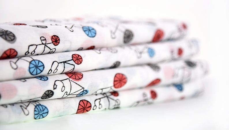 May include: A stack of white fabric with a repeating pattern of black bicycles with red and blue wheels.