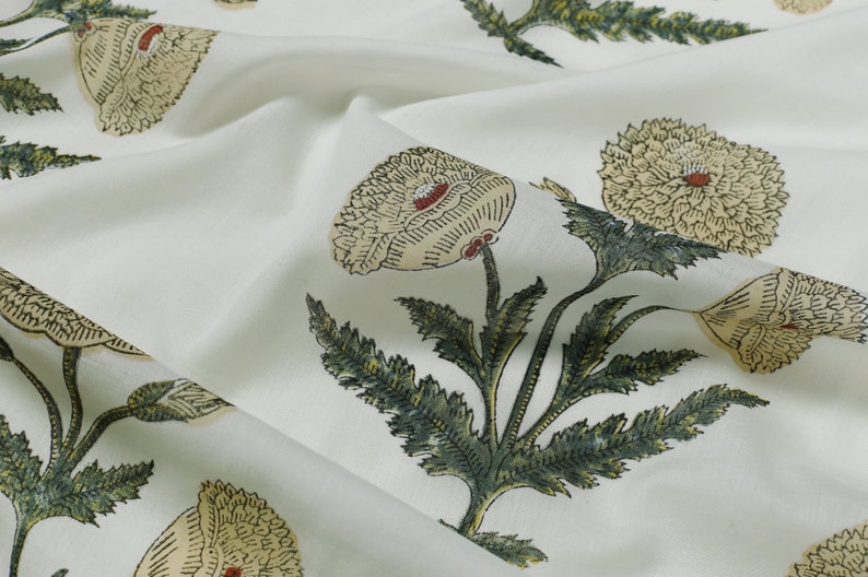 Op de afbeelding: Witte stof met een bloemenprint met grote, gestileerde bloemen in tinten beige, groen en rood. De bloemen hebben een gelaagde, textuurrijke uitstraling.