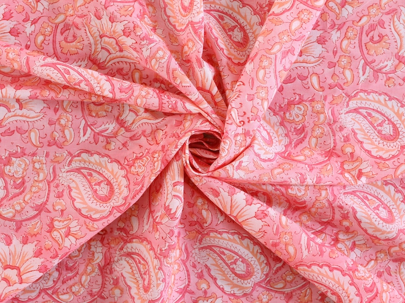 Puede incluir: Tela rosa con un patr&oacute;n de paisley. La tela est&aacute; doblada y retorcida, mostrando los intrincados detalles del dise&ntilde;o.