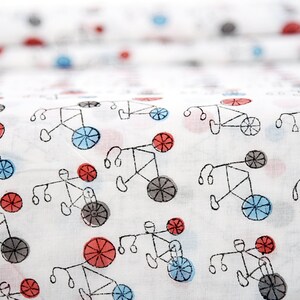 May include: White fabric with a repeating pattern of black bicycles with red and blue wheels. The bicycles are drawn in a simple, childlike style.