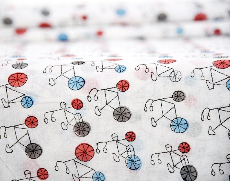 May include: White fabric with a repeating pattern of black bicycles with red and blue wheels. The bicycles are drawn in a simple, childlike style.