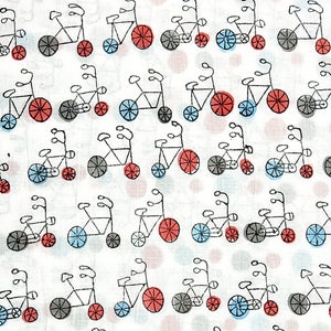 May include: A white fabric with a repeating pattern of black tandem bicycles with red and blue wheels. The background is a light gray with small pink and white dots.
