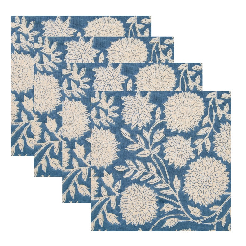 Puede incluir: Juego de cuatro servilletas de algod&oacute;n azul con un patr&oacute;n floral blanco. Las servilletas est&aacute;n dobladas y apiladas una encima de la otra.