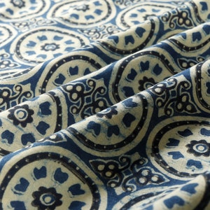 K&ouml;nnte beinhalten: Blauer und wei&szlig;er Stoff mit einem sich wiederholenden Muster aus stilisierten floralen Motiven. Der Stoff hat eine strukturierte, handgewebte Optik.